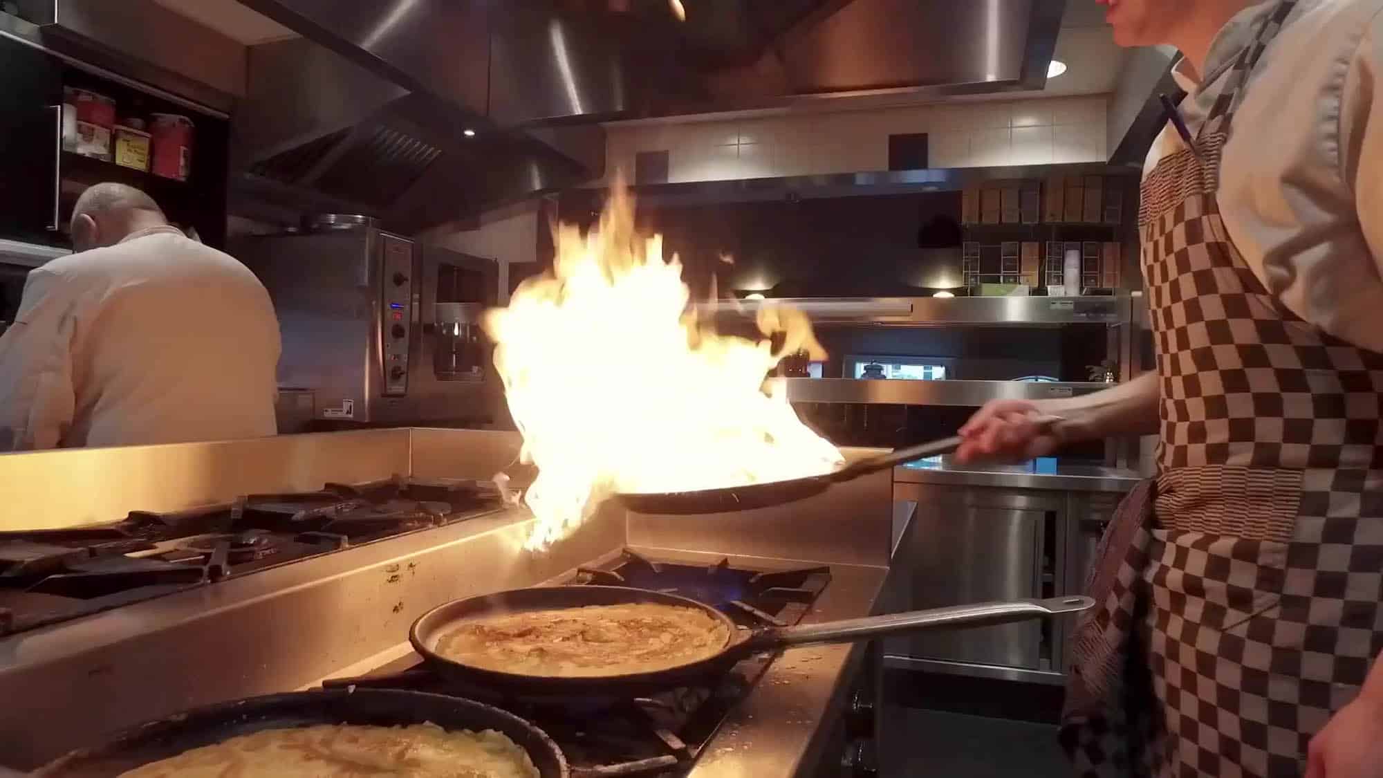 Kok flambeert boven de pannenkoekenpannen in de keuken van De Zaagkoele